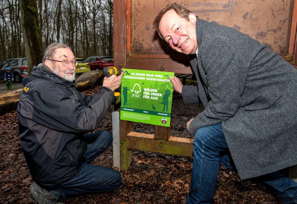 Grüne Hinweisschilder informieren künftig die Besucher im Stadtwald über die FSC-Zertifizierung. Joachim Boller, Vorsitzender des Umweltausschusses, und Bürgermeister Steffen Mues befestigten jetzt das erste Schild im Historischen Tiergarten.